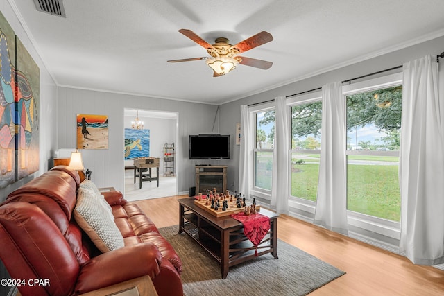 living room with ceiling fan with notable chandelier, wood-type flooring, a textured ceiling, and crown molding