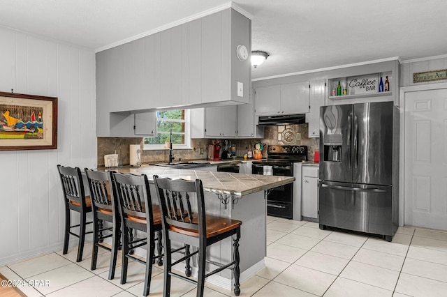 kitchen featuring wood walls, sink, kitchen peninsula, black appliances, and a kitchen bar