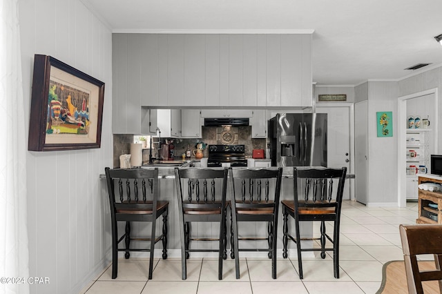 kitchen featuring black / electric stove, stainless steel fridge, light tile patterned floors, and tasteful backsplash