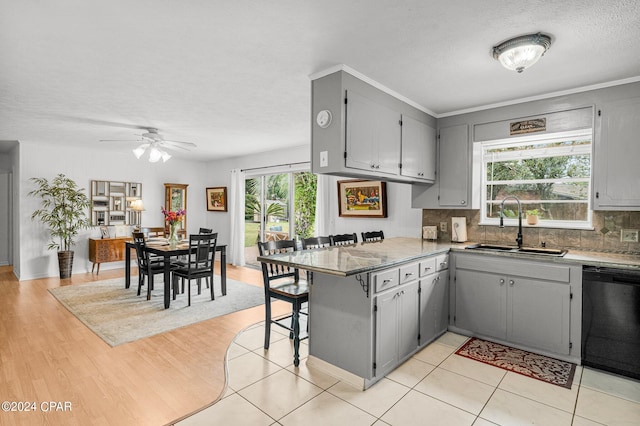 kitchen featuring gray cabinetry, kitchen peninsula, dishwasher, and a wealth of natural light