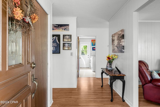 hallway with ornamental molding, light wood-type flooring, and wood walls