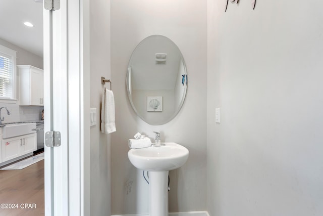 bathroom featuring wood-type flooring, decorative backsplash, and sink