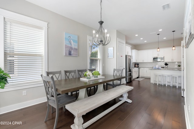 dining area with a healthy amount of sunlight, dark wood-type flooring, and a notable chandelier