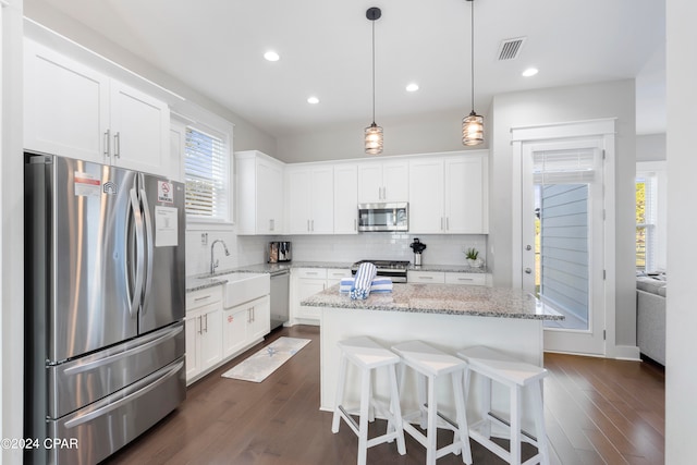 kitchen featuring light stone counters, white cabinets, stainless steel appliances, and a kitchen island