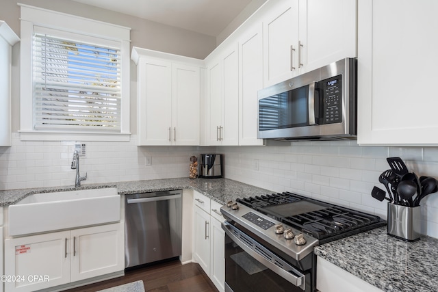 kitchen with light stone counters, appliances with stainless steel finishes, white cabinetry, and sink