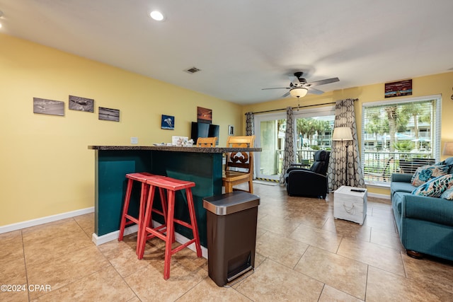 kitchen featuring ceiling fan, a breakfast bar area, and light tile patterned floors