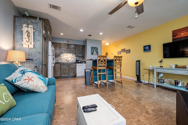 living room featuring a textured ceiling, ceiling fan, light tile patterned flooring, and sink