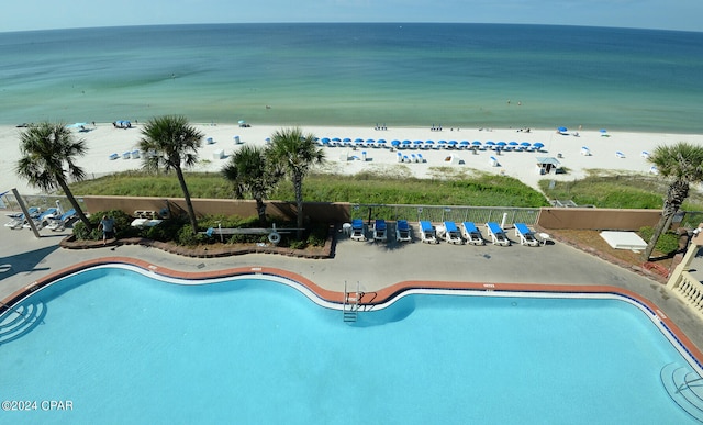 view of swimming pool featuring a beach view, a patio, and a water view