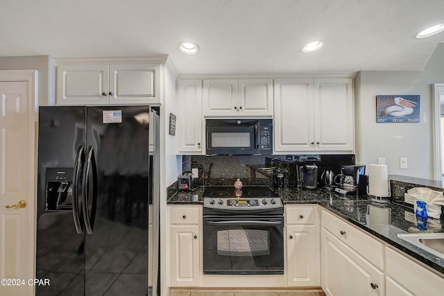 kitchen featuring white cabinetry, dark stone counters, and black appliances