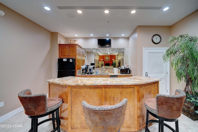 bar featuring light stone counters, sink, and black appliances