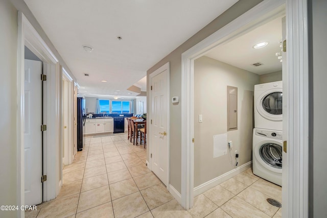 laundry area with stacked washer / dryer and light tile patterned floors