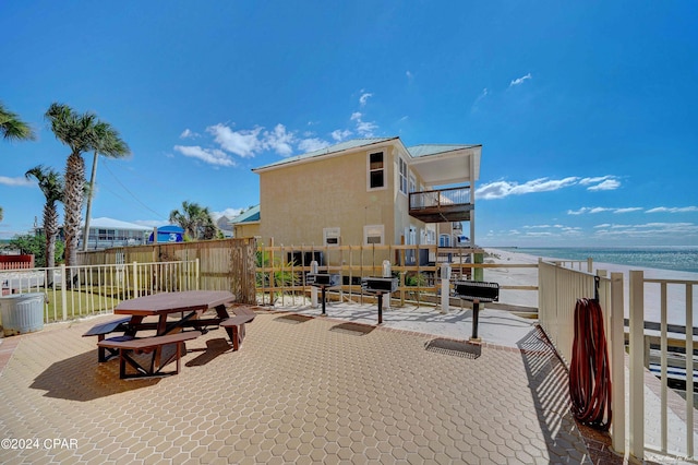 view of patio with a beach view, a balcony, and a water view