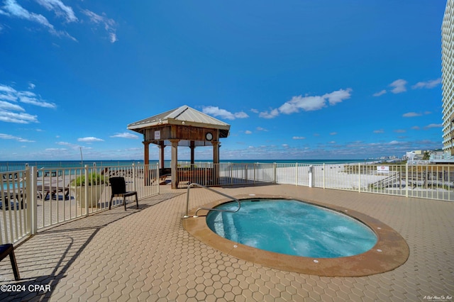 view of pool featuring a community hot tub, a water view, a view of the beach, and a gazebo