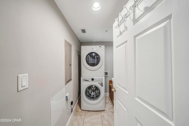 laundry room featuring stacked washer and clothes dryer and light tile patterned floors