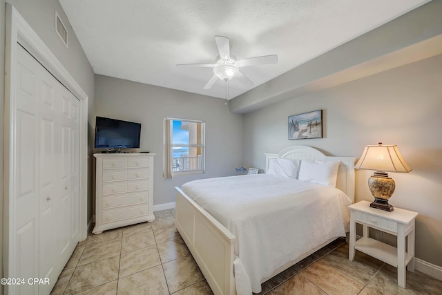 tiled bedroom with ceiling fan, a closet, and a textured ceiling