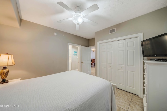 tiled bedroom featuring ceiling fan and a closet