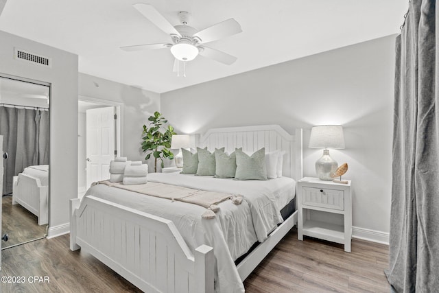 bedroom featuring a ceiling fan, wood finished floors, visible vents, and baseboards