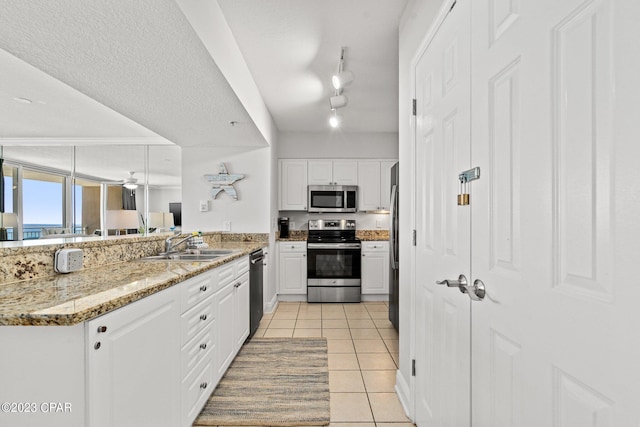 kitchen featuring a sink, appliances with stainless steel finishes, white cabinets, and light tile patterned floors