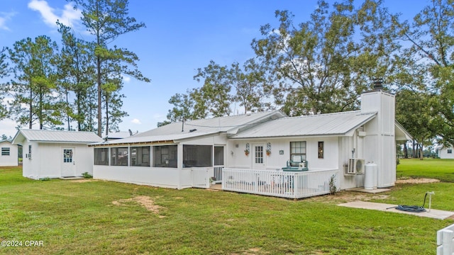 rear view of property featuring a sunroom, ac unit, and a yard