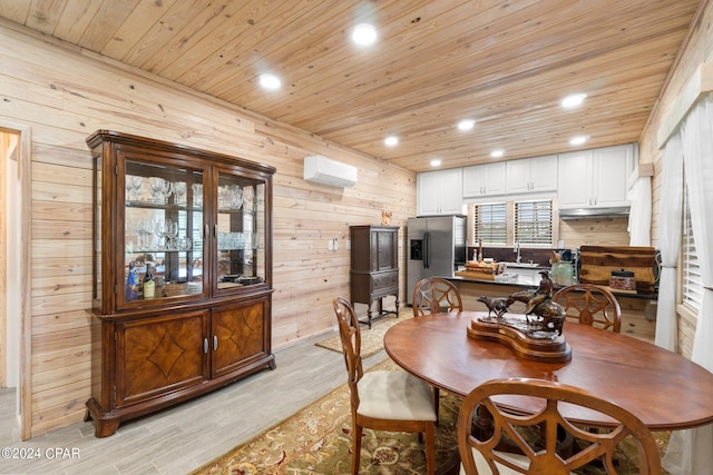 dining space featuring light wood-type flooring, sink, wood walls, a wall mounted air conditioner, and wooden ceiling