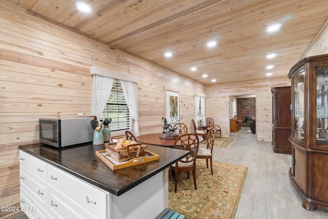 kitchen featuring light wood-type flooring, white cabinets, a kitchen island, wooden walls, and wooden ceiling