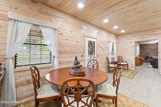 dining space featuring wood ceiling, wooden walls, light hardwood / wood-style floors, and a fireplace