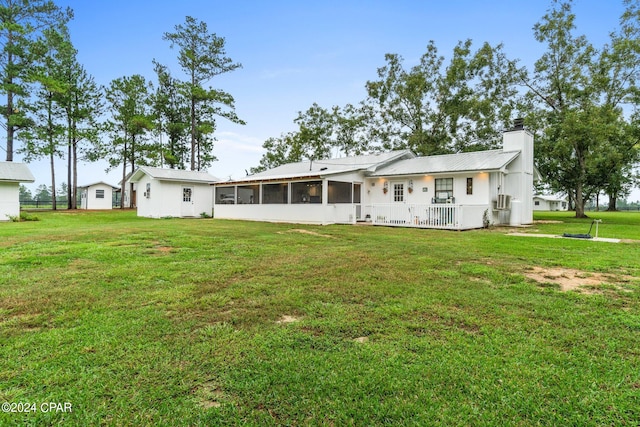 back of property with a lawn and a sunroom