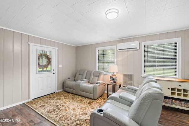 living room with wooden walls, dark hardwood / wood-style floors, a wall mounted air conditioner, and a healthy amount of sunlight