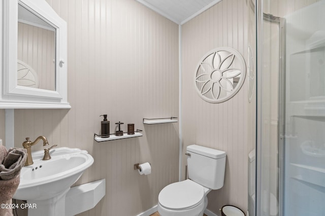 bathroom featuring ornamental molding, toilet, sink, and an enclosed shower