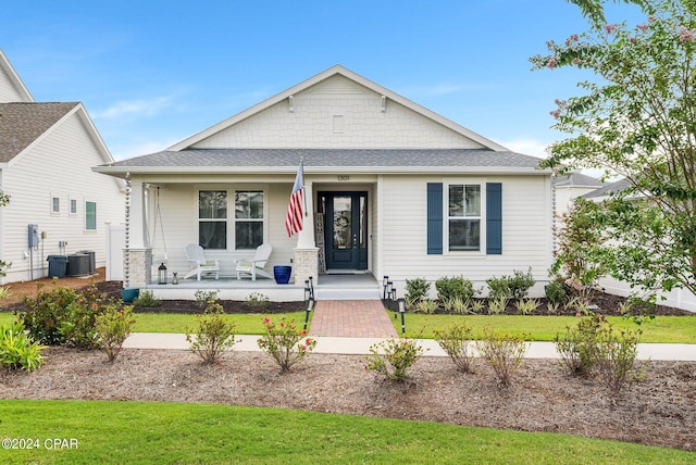 view of front of home featuring central AC, a front lawn, and covered porch