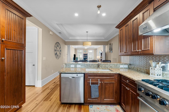 kitchen with appliances with stainless steel finishes, kitchen peninsula, exhaust hood, light hardwood / wood-style flooring, and sink