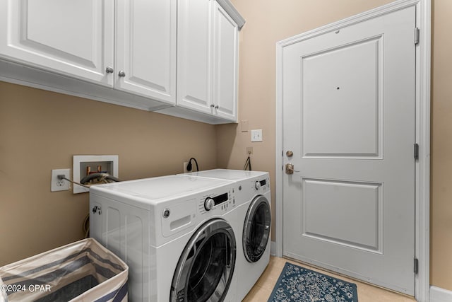 clothes washing area featuring washing machine and dryer, light tile patterned floors, and cabinets