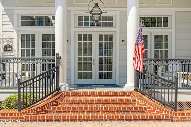 view of exterior entry featuring french doors and a porch