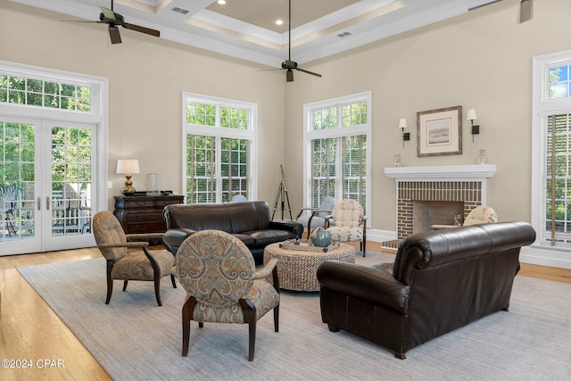 living room featuring light wood-style floors, a brick fireplace, crown molding, and a towering ceiling