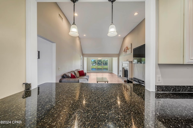 kitchen with dark stone countertops, high vaulted ceiling, and decorative light fixtures