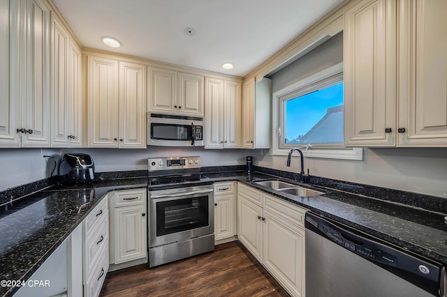 kitchen with dark hardwood / wood-style flooring, stainless steel appliances, dark stone counters, and sink