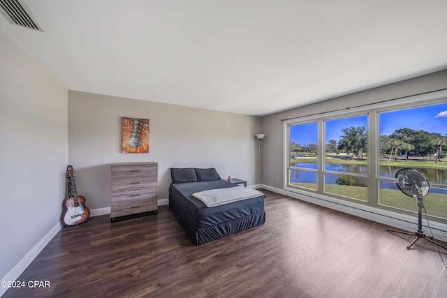 bedroom featuring a water view and dark wood-type flooring