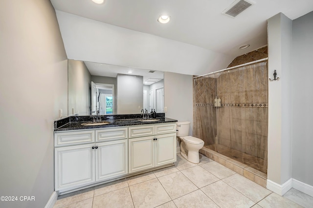 bathroom featuring a tile shower, tile patterned flooring, lofted ceiling, vanity, and toilet