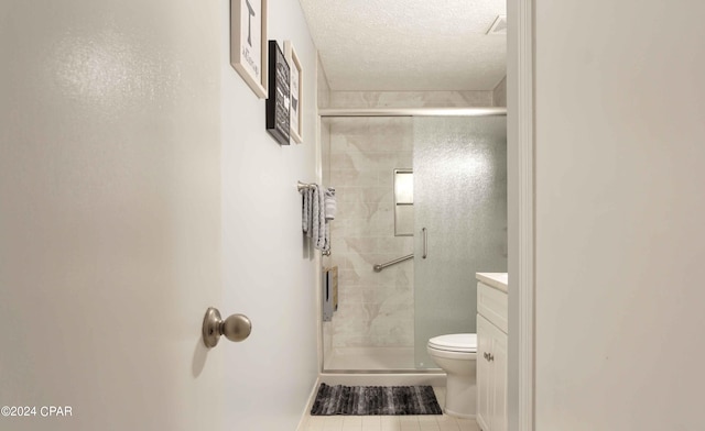 bathroom featuring vanity, a textured ceiling, a shower with door, toilet, and tile patterned floors