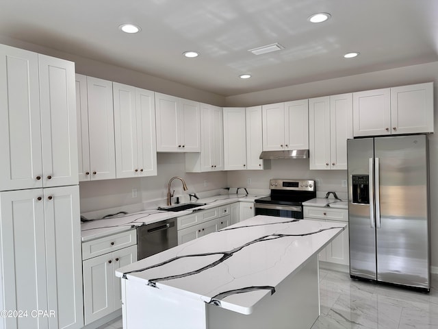 kitchen featuring light stone counters, a center island, sink, white cabinetry, and stainless steel appliances