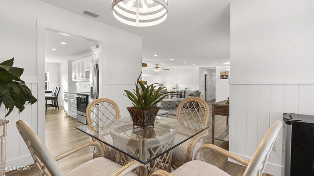 dining space featuring ceiling fan with notable chandelier and light hardwood / wood-style floors