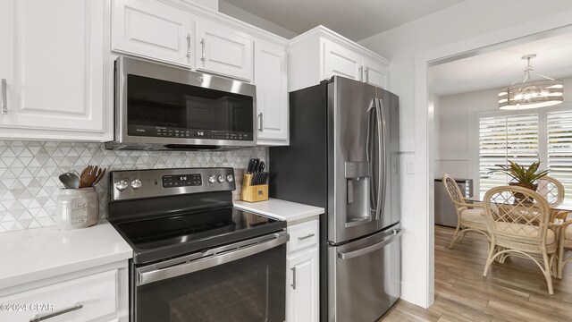 kitchen featuring appliances with stainless steel finishes, light hardwood / wood-style floors, a chandelier, and white cabinets