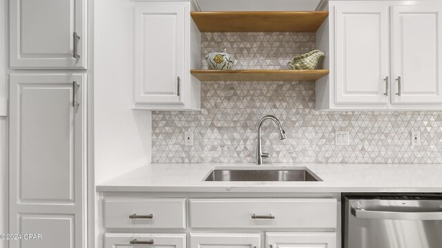 kitchen featuring backsplash, white cabinetry, dishwasher, and sink