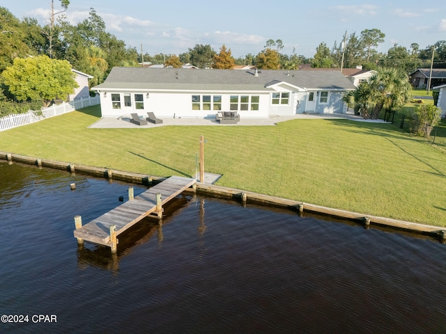 view of dock with a water view, a lawn, and a patio area