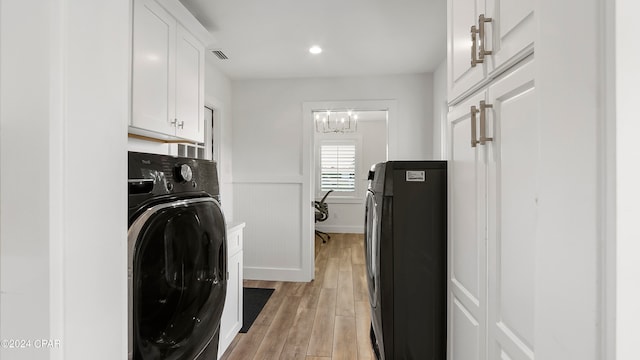 laundry room featuring light hardwood / wood-style flooring, cabinets, and an inviting chandelier