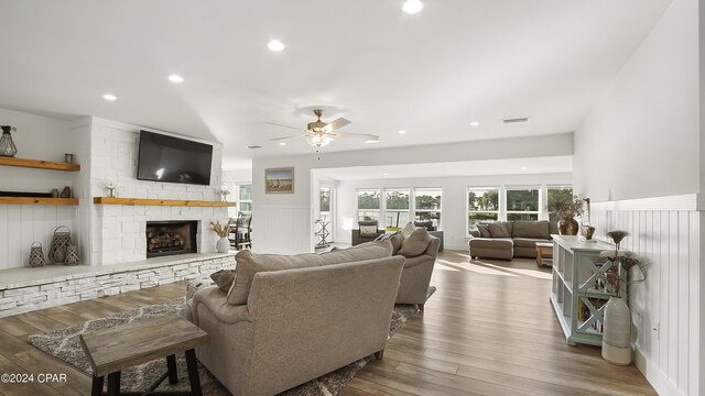 living room featuring ceiling fan, hardwood / wood-style flooring, and a fireplace