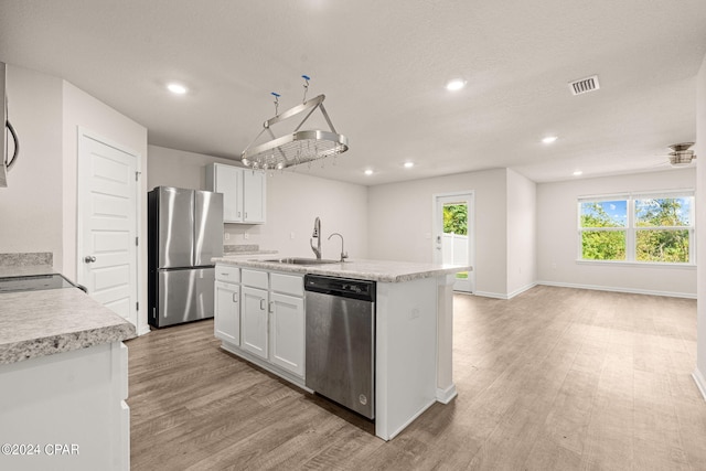 kitchen with stainless steel appliances, white cabinetry, light hardwood / wood-style floors, and sink