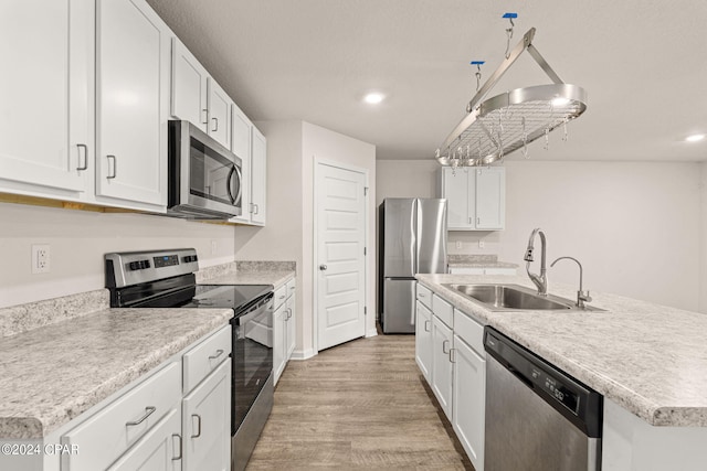 kitchen with appliances with stainless steel finishes, a center island with sink, light hardwood / wood-style flooring, and white cabinets