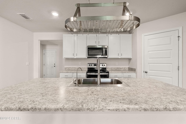 kitchen with white cabinets, a textured ceiling, and stainless steel appliances