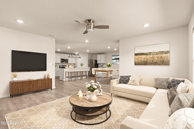 living room featuring ceiling fan, light hardwood / wood-style flooring, and sink